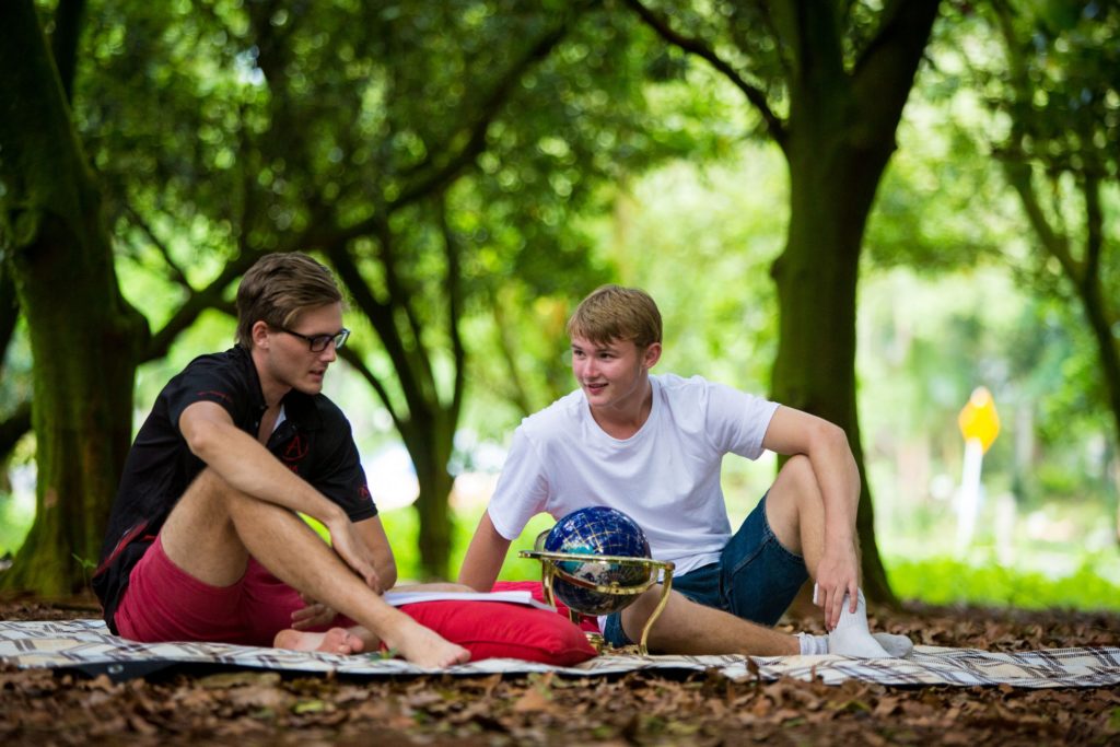 Year 11 student and his tutor reading a workbook in a park