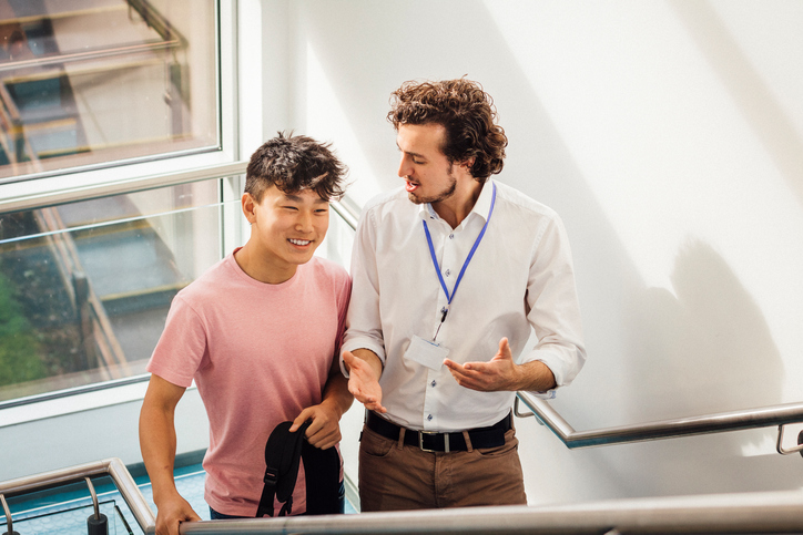 Tutor and student talking in school stairwell